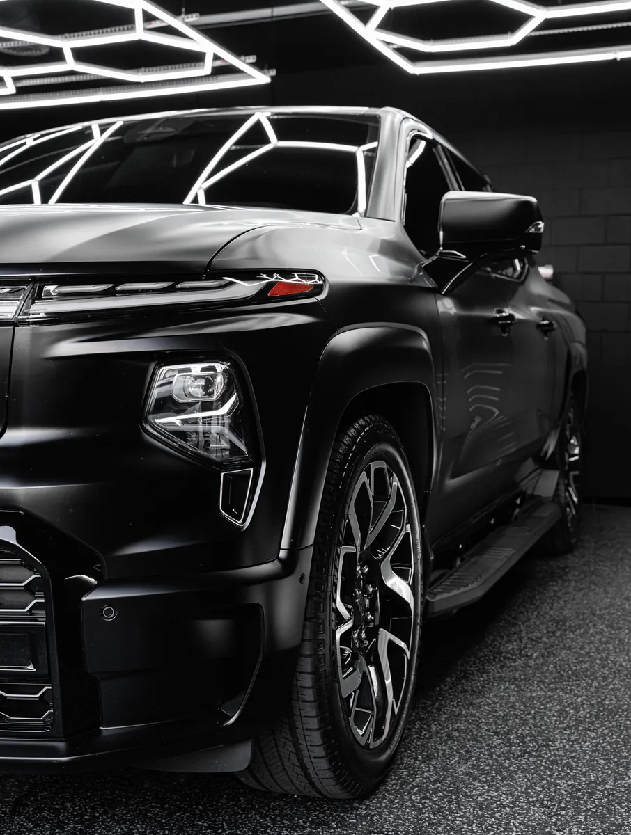 Headlight, front fender and wheel of a satin black Chevrolet Silverado EV RST