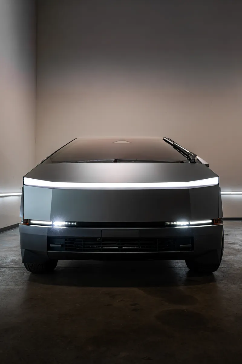 Front of a grey-olive Tesla Cybertruck with the light bar on