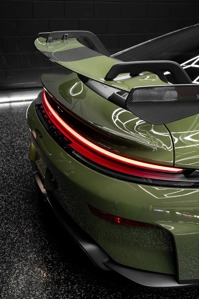 Rear of an olive green Porsche 911 GT3 showing the light bar and wing