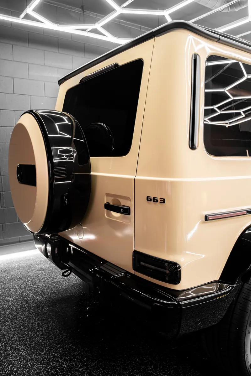 Rear of a beige Mercedes-AMG G63 with a gloss black spare wheel cover