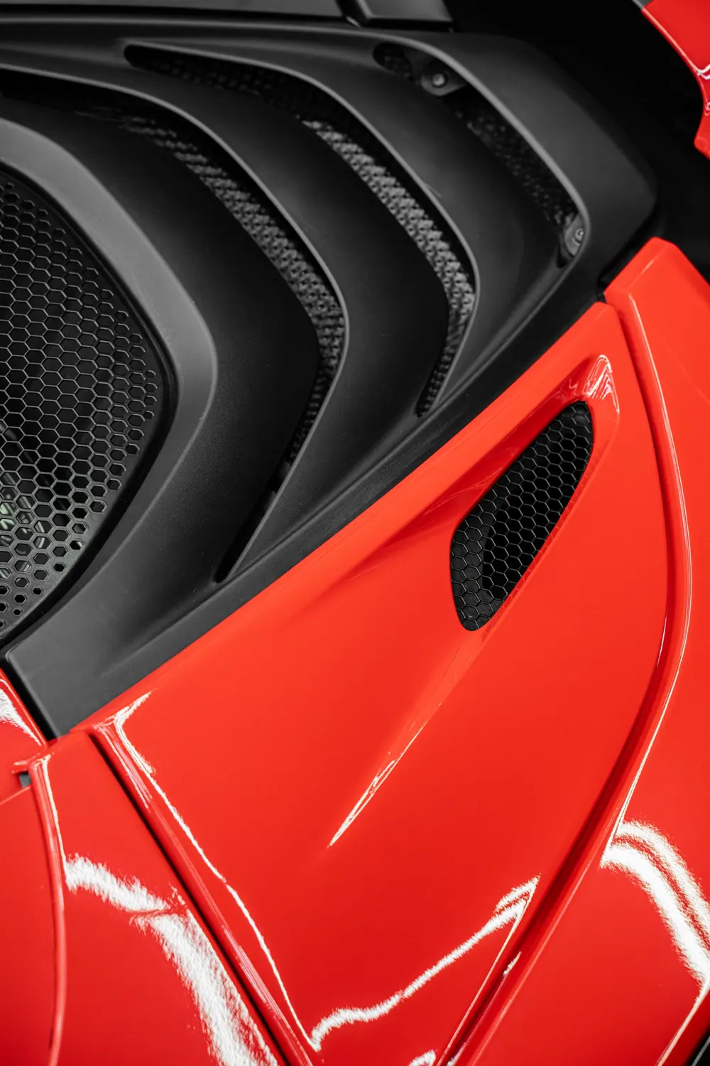 Close-up of red gloss film meeting matte black trim on a McLaren