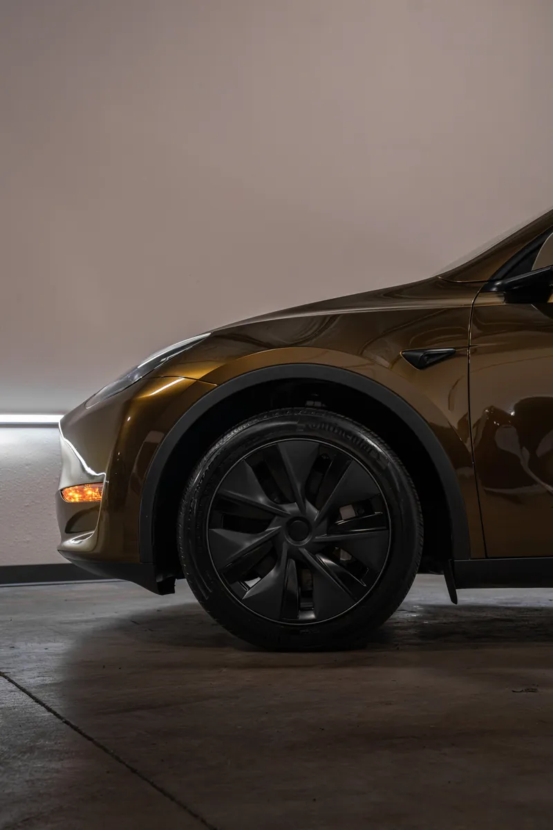 Front wheel and fender of a bronze Tesla Model Y