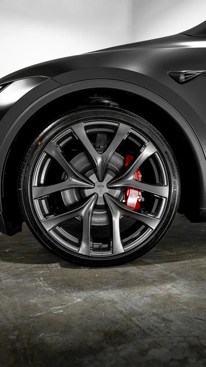 Front wheel and fender of a satin Tesla Model Y Performance with red brake calipers